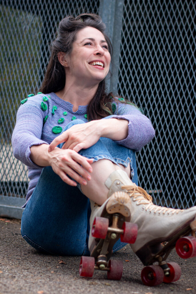 smiling woman in roller skates wearing the Circle Dance Sweater