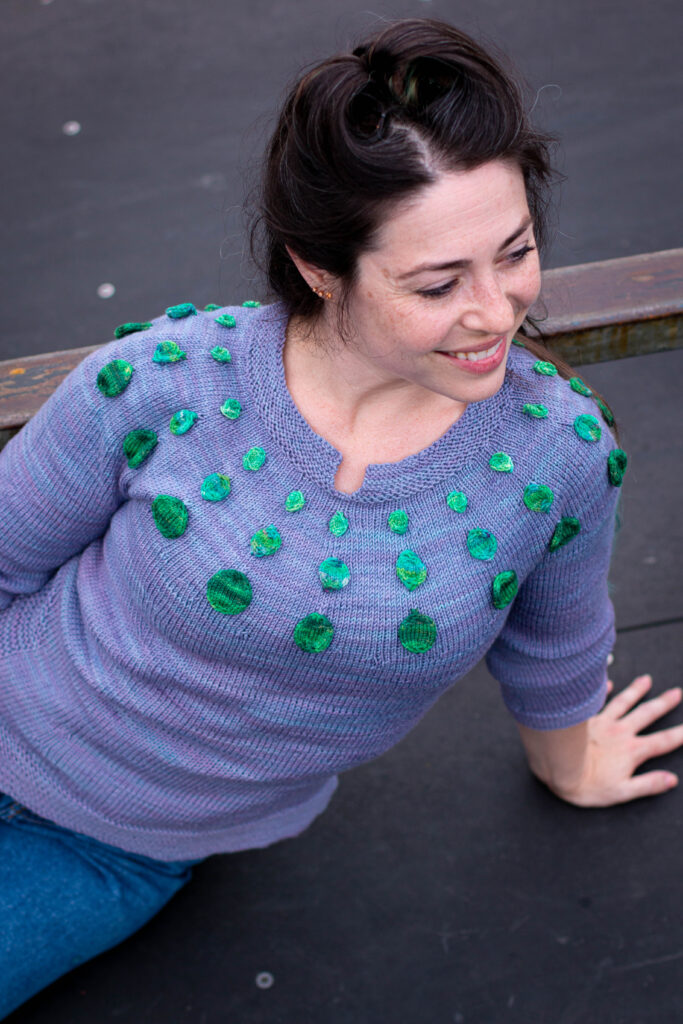 Woman leans on one hand modeling the Circle Dance Sweater