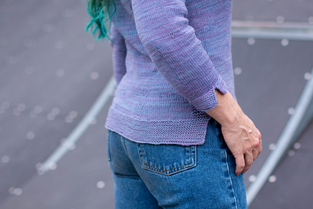 Side view of Circle Dance Sweater showing sleeve vent and hip vent with a swish of long hair dyed green