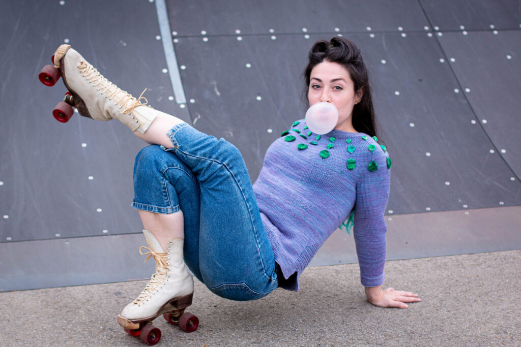 Woman poses on roller skates while blowing bubbles wearing the Circle Dance Sweater