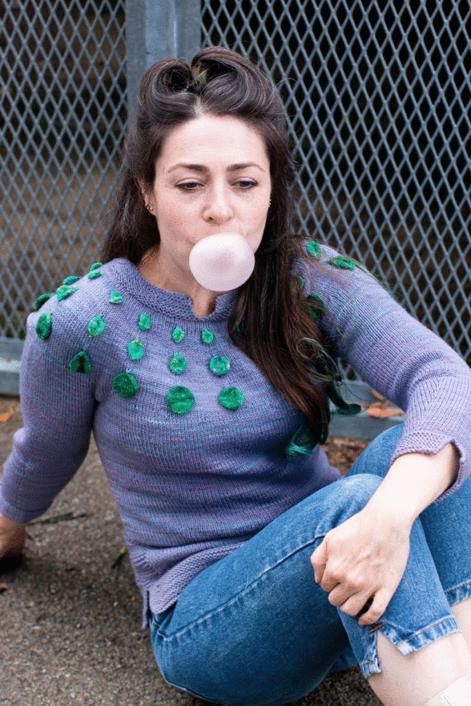 woman blowing bubble gum wearing the Circle Dance Sweater