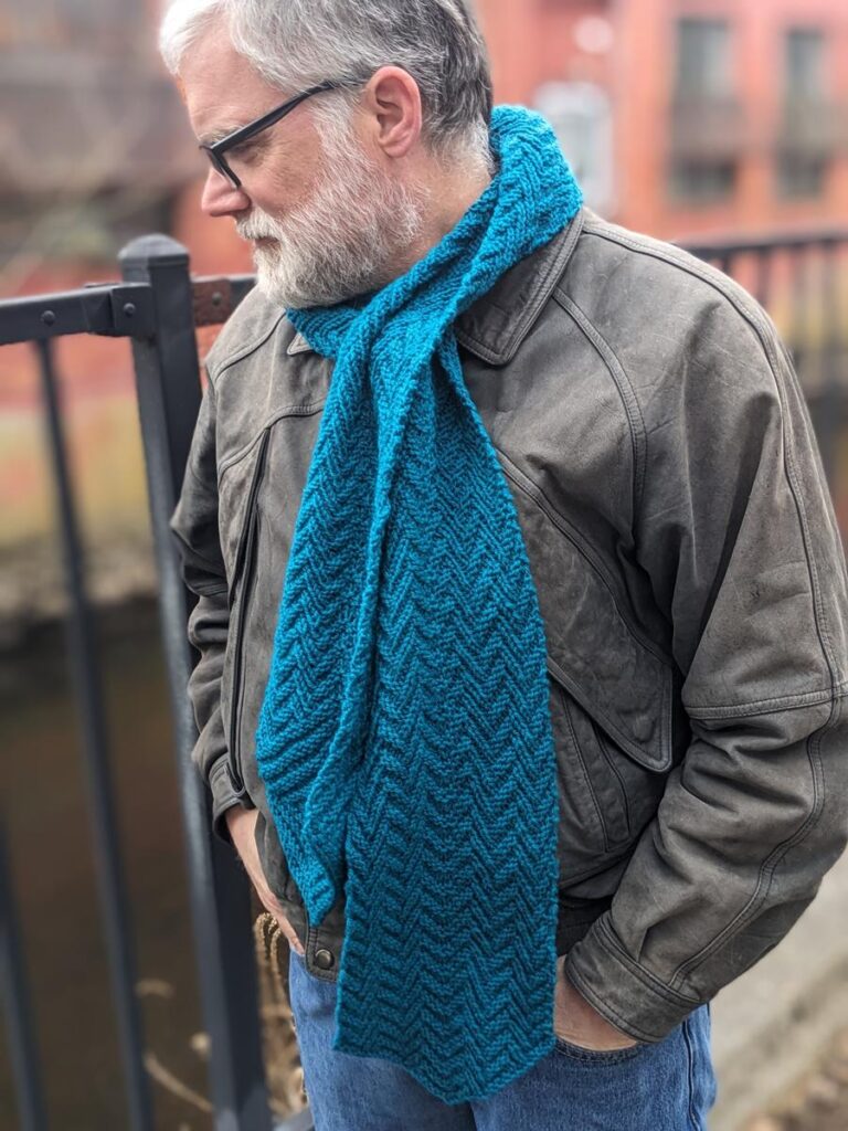 Man wears Herringbone Hexagonal Scarf near canal